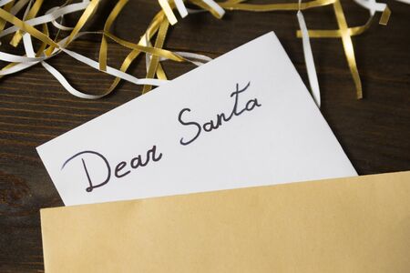 Letter for Santa in an envelope. Tinsel on wooden background. Close up