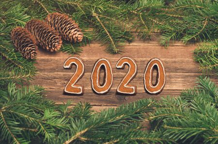 Number 2020 from gingerbread cookies. Wooden background with fir branches and cones on the edge of the frameの写真素材