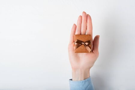 Brown jewelry box in female hand. Present. White backgroundの写真素材
