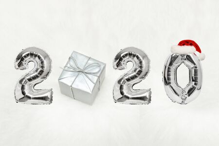 Number 2020 of silver balloons with Santa hat. Gift box. White background. New years concept