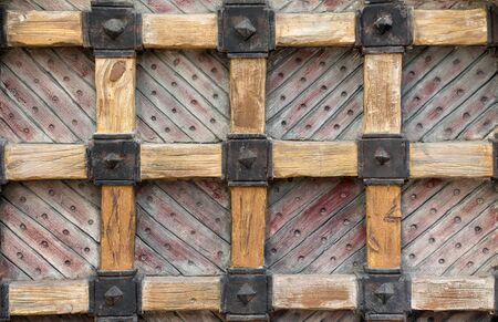 Elements of massive old wooden gate with grid of thick beams. Close up.