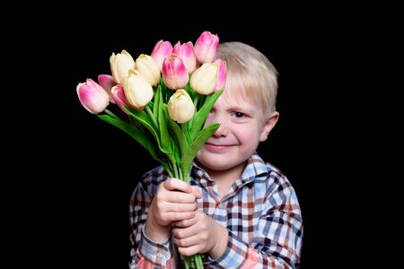 Portrait smiling blond boy with a bouquet of tulips. Black backgroundの写真素材