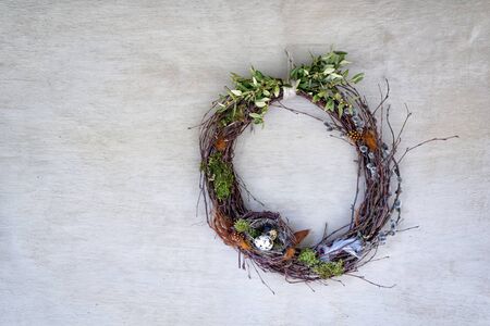 Bird's nest with two eggs on a wreath of willow twigs against a gray plastered wall. Directly above.の写真素材