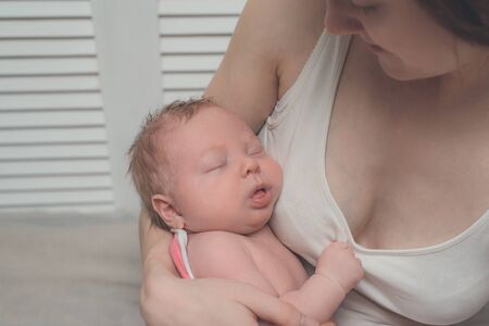 Mother with a blond sleeping baby in her arms, a moment of tenderness. Close-up