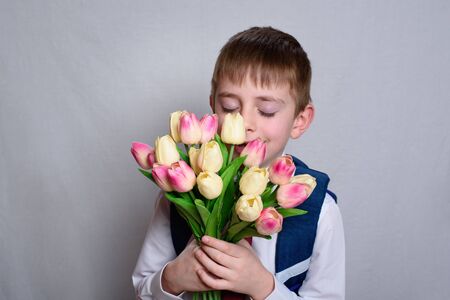 Schoolboy with a school bag holding a bouquet of tulips. White backgroundの写真素材