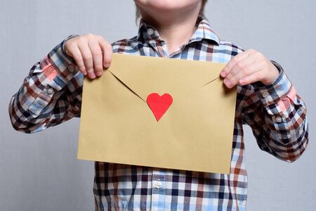 Large envelope with a red heart in children's hands. Close-upの写真素材