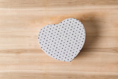 White box shape of heart on a wooden background. Symbol of love