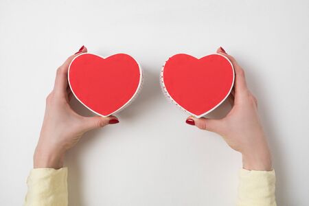 Two small red heart shaped boxes on female hands on white background. Gift for Valentine's day.の写真素材