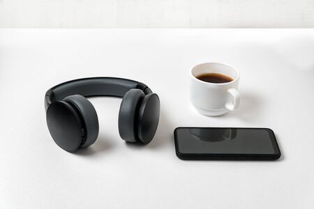Wireless full-size headphones, smartphone and cup of coffee on white backgroundの写真素材