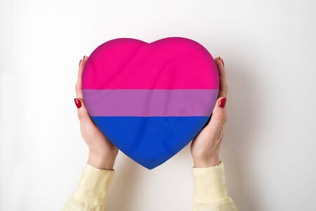LGBT bisexual pride flag on a heart shape box in female hands. Pride symbol. Top viewの写真素材