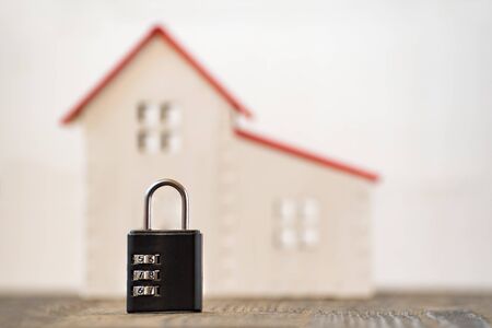 Model home and lock on a white background. Home and security concept. Blurred background