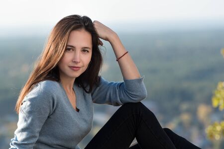 Portrait of a beautiful pensive girl outdoors. Forest in the distance, sunny dayの写真素材