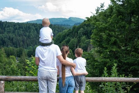 Mother, father and two children on nature background. Rest of the city. Back view.の写真素材