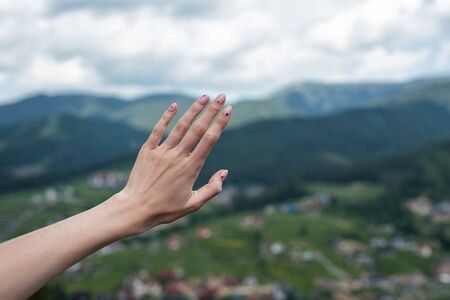 Female hand on naturebackground. reach the mountains. Travel manicure.の写真素材