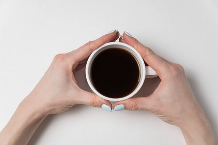 Female hands holding cup of strong coffee on white background. Morning coffee