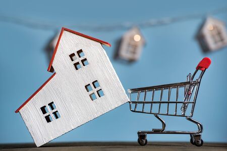 Home and shopping cart. Mortgage buying house concept. Blue background front viewの写真素材