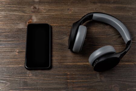 Headphones and phone on a dark wooden background. Gadgets of the modern manの写真素材