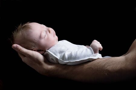 Baby lying on fathers arms. Newborn and dad. Side view closeup isolated