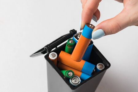 Female hand throws the used battery in the trash. Collection and recycling concept used batteries
