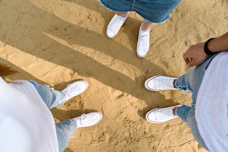 Shoes selfie from above. Teenagers stand on sand in white sneakers. Top view.の写真素材