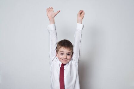 Little boy in shirt and tie raised his hands up. Middle School, Junior High School.の写真素材
