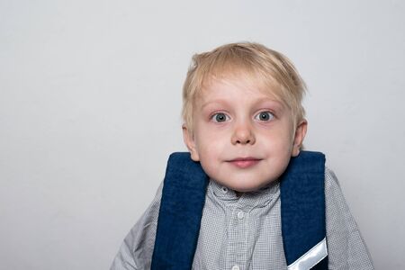 Cute fair-haired boy with surprised look on white background. Portrait.