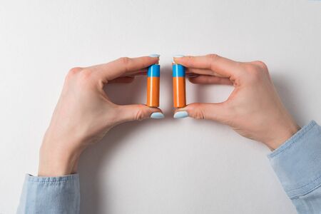 woman hands holding two AA batteries on white background. Generic accumulator.の写真素材