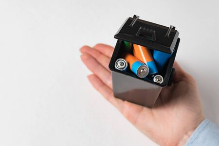 Used batteries in the trash in female hand. High danger for the environment. Proper disposal of...