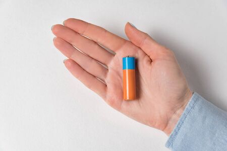 AA alkaline battery lying on the women's hands. Generic accumulator on white background.の写真素材