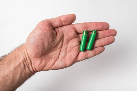Two AA batteries are on the men's palms on white background. Accumulatorsの写真素材
