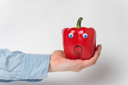 Large red bell pepper, Googly eyes on palm. Scared pepper character. White backgroundの写真素材