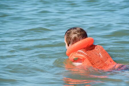 Boy in life jacket learn to swim. Safe sea vacation with children.の写真素材