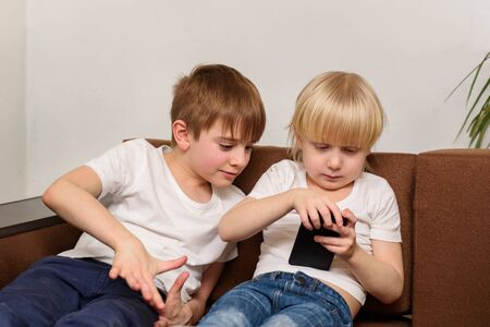 Two children use telephone. Kids and gadgets addiction concept.