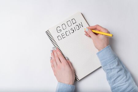 Top view of woman writes in notebook the inscription GOOD DECISION. Top view.の写真素材