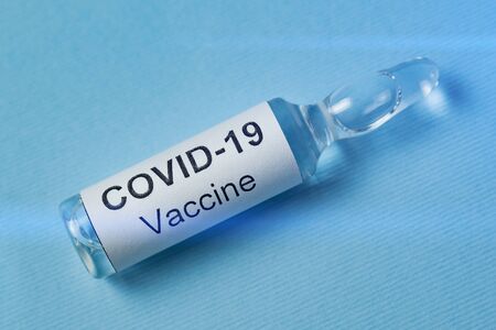 Vaccine COVID-19. Treatment from flu nCoV 2019. Ampule with medication on blue background.の写真素材