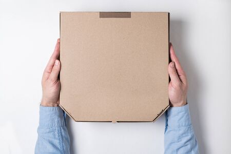 Top view of male hands and box of pizza on white background. Concept of food delivery to home.