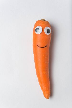 Funny carrot character with Googly eyes and smile on white background. Vertical frame.の写真素材