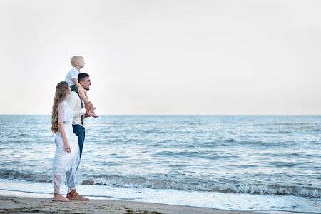 Beautiful couple in love walking on the ocean. Travel with young child. Happy parenthood.の写真素材