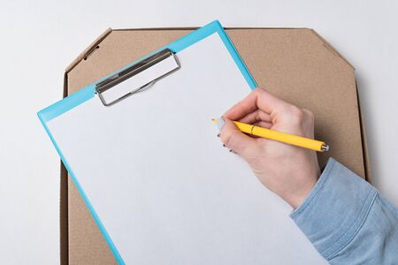 Female hand signs document on background of box. Parcel delivery concept.