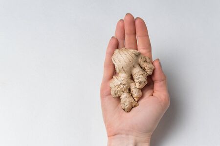 Ginger root lies in female hands on white background. Products for health and energy.の写真素材
