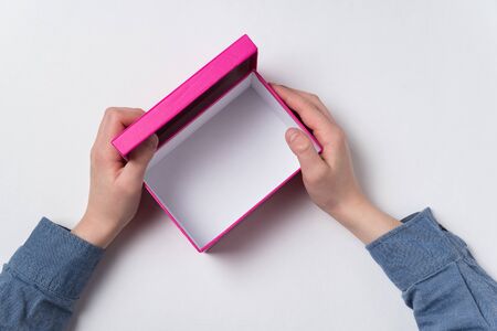 Open pink carton box in children's hands. Top view, white backgroundの写真素材