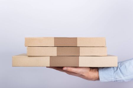 Hand holding pizza boxes on white background. Side View. Courier delivery.