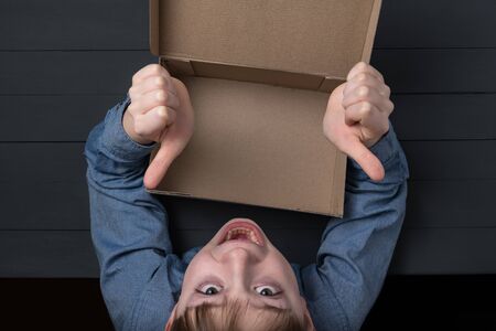 Funny boy with an open empty box shows thumbs up. Top view.の写真素材
