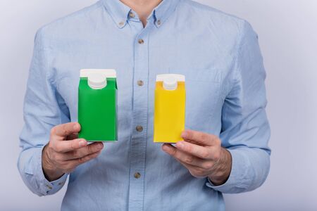 Green and yellow cartones milk or juice in mens handsの写真素材