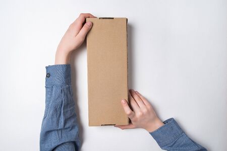 Craft paper box in children's hands on white background. Top view. Copy space
