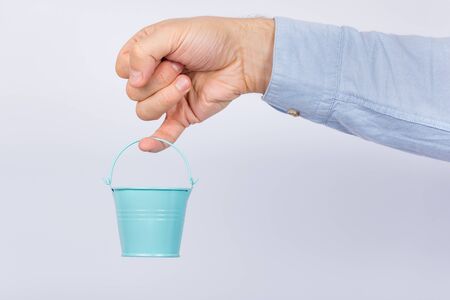 Man with little finger holding small toy bucket on white backgroundの写真素材