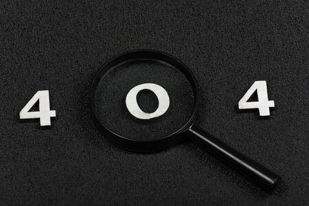 Numerals 404 and magnifying glass on black background. Error conceptの写真素材