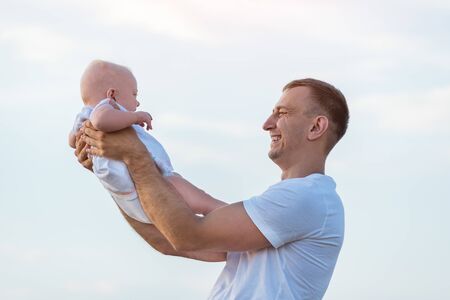 Happy young father holding baby against the sky. Portrait of dad and childの写真素材