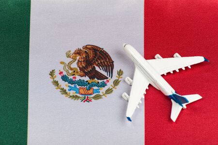 Flag of Mexico and model airplane. Resumption of flights after quarantine. Travel to Mexico.