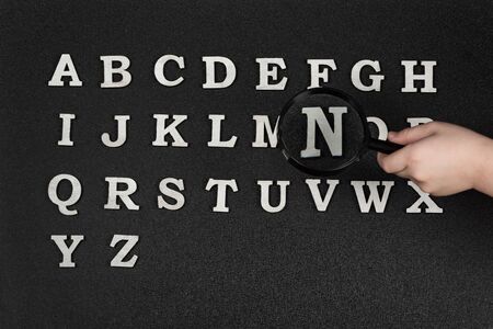Collection of English letters alphabetical order from A to Z. Hand holding magnifying glass over lettersの写真素材
